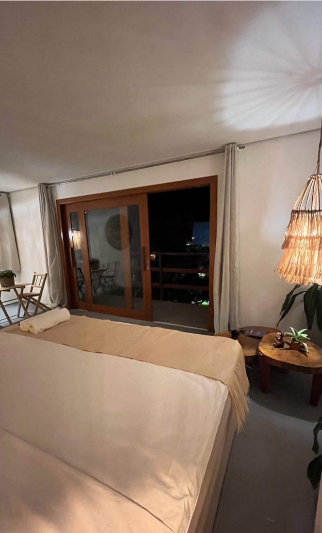 Cama à noite com a porta de vidro aberta para a varanda