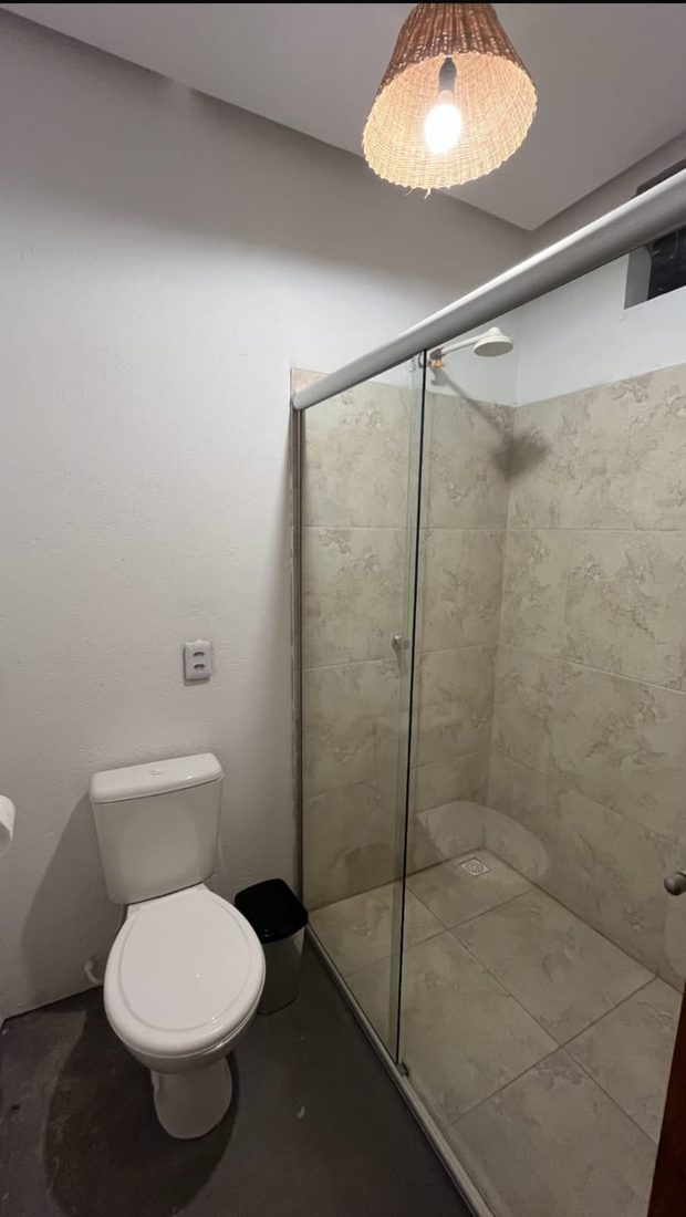 Box de banheiro com chuveiro e piso em tons claros