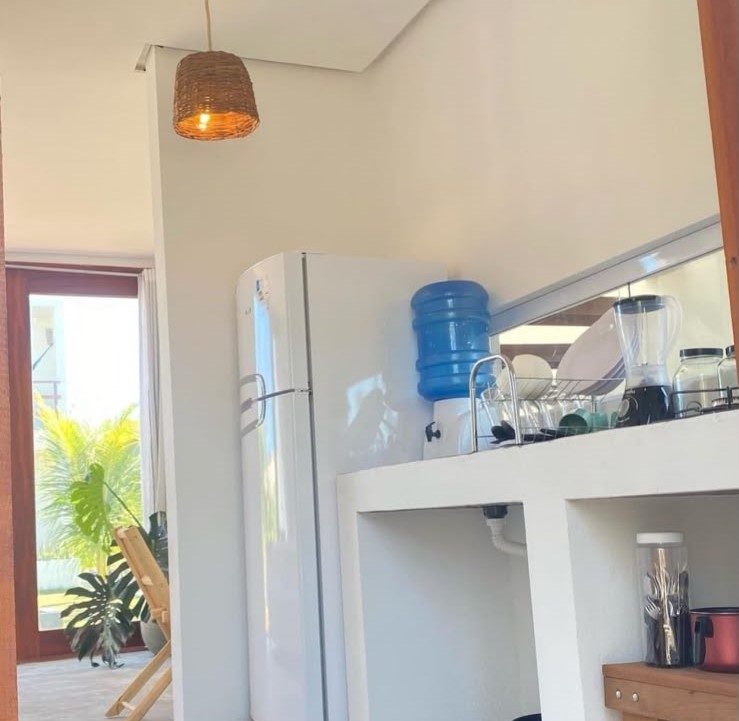 Cozinha compacta com geladeira e galão de água