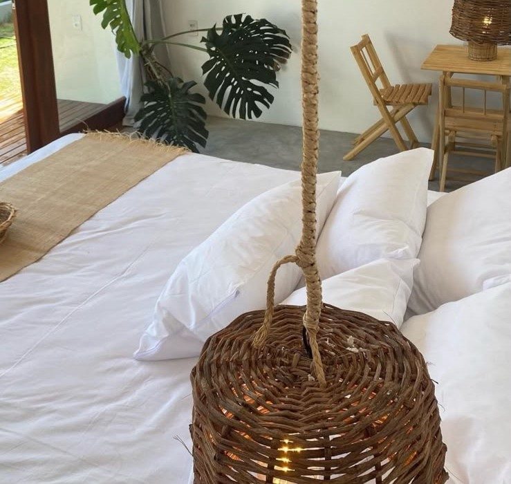 Cama com travesseiros e luminária de fibra pendurada