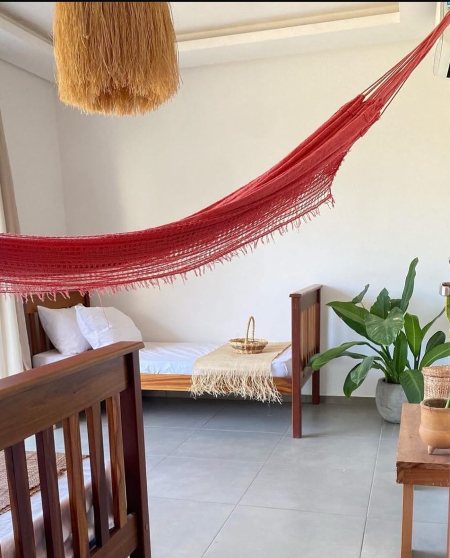 Quarto com rede vermelha e duas camas de solteiro