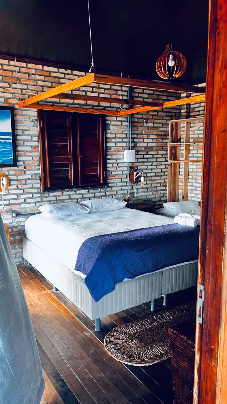 Quarto de casal com parede de tijolo aparente